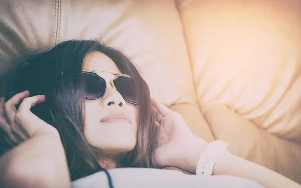 Азиатки в солнечных очках, лежащие на диване и слушающие музыку — стоковое фото