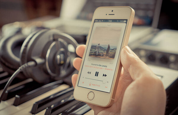 Musician using his iPhone to listen to music on Apple Music.