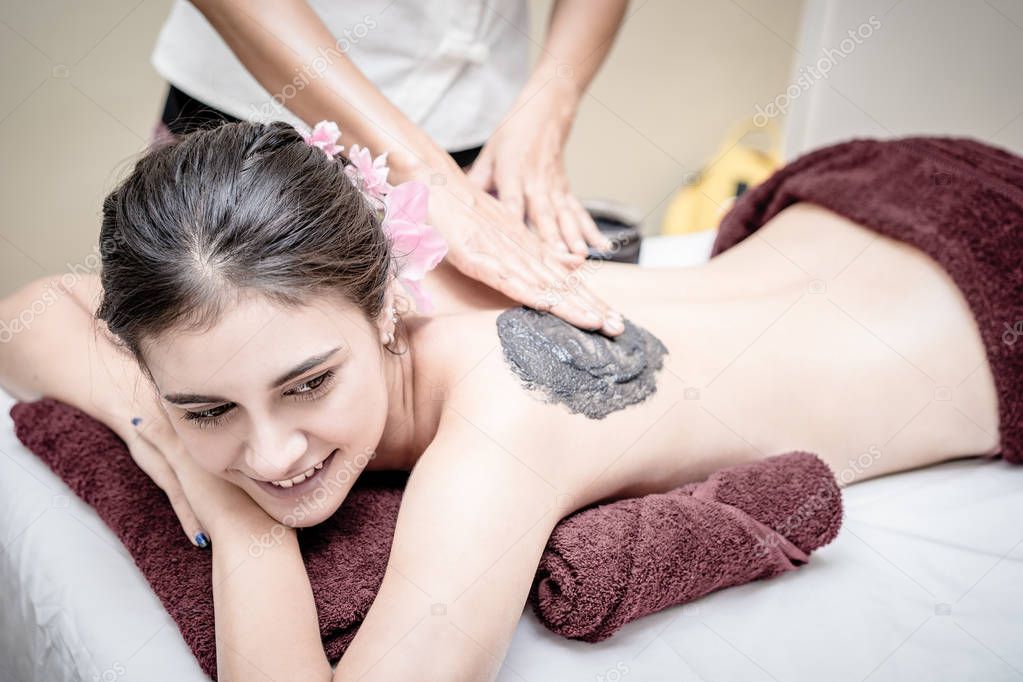 Women is getting Charcoal scrub skin treatment in Spa