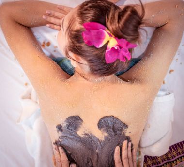 Women is getting charcoal scrub on her back clipart