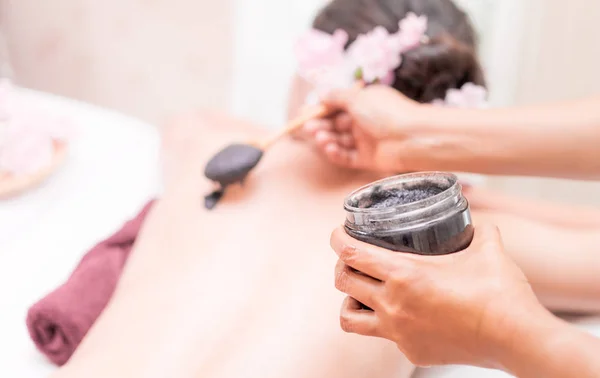Spa terapist bir kadın için kömür kil geri koyuyor