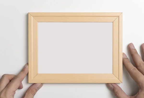 Mãos segurando moldura de foto de madeira em branco para simular — Fotografia de Stock