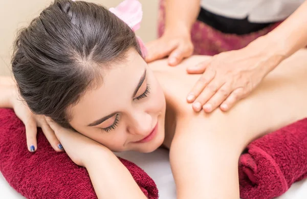 Mujer feliz está recibiendo masaje en una cama de spa con un ambiente de tonificación roja —  Fotos de Stock