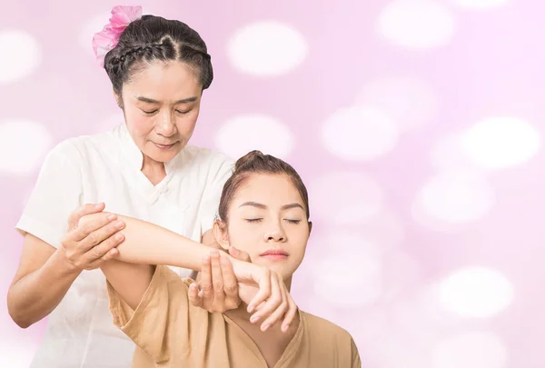 Thai Massage Therapist is massaging girl shoulder on pink bokeh — Stock Photo, Image