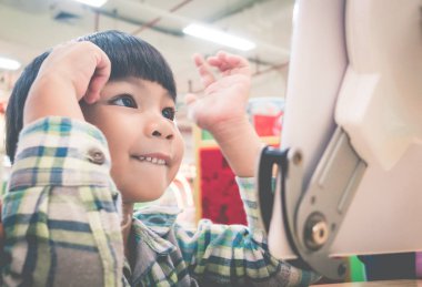 Asyalı çocuk tablet ekranında ne heyecanlı gülümsüyor