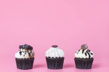 Pembe kopya alanı üzerinde üç çikolatalı mini kek