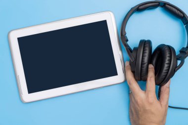 Boş tablet kulaklık müzik ve video akışı kavramı için tutan el ile