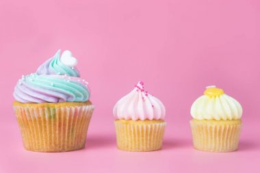 Gökkuşağı pastel çörekler ve pembe bir arka plan üzerinde mini kek