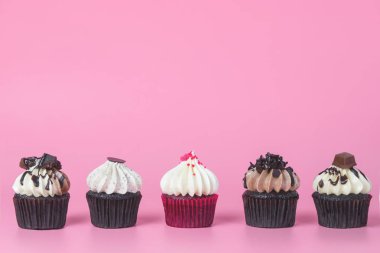Orta pembe bir arka plan üzerinde kırmızı cupcake ile beş çikolatalı kek