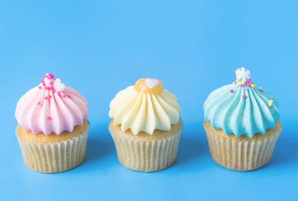 Three colorful fancy cupcake on blue background