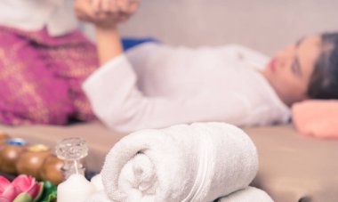 Kadın beyaz havlu ve spa ekipmanları ön plan üzerinde masaj
