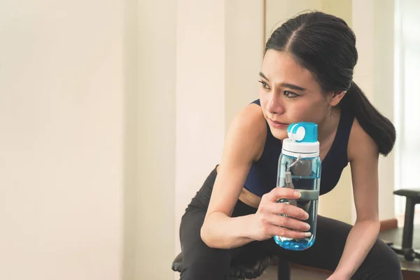 Sport woman is drinking fresh water while exercising in fitness