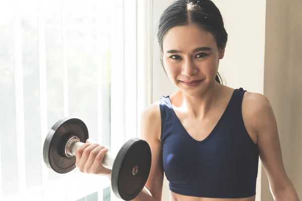 Strong Asian skinny woman is lifting dumbbell in fitness