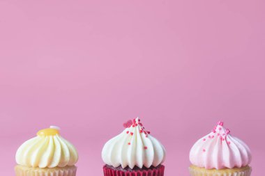 Pembe arka plan, pastel tonu üzerinde üç Mini süslü cupcake