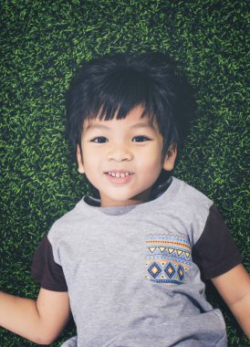 Bir çim yerde yatarken mutlu Asyalı çocuk