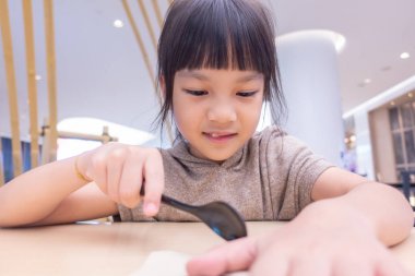 Asyalı çocuk restoranda yemek yemeye kaşık kullanarak