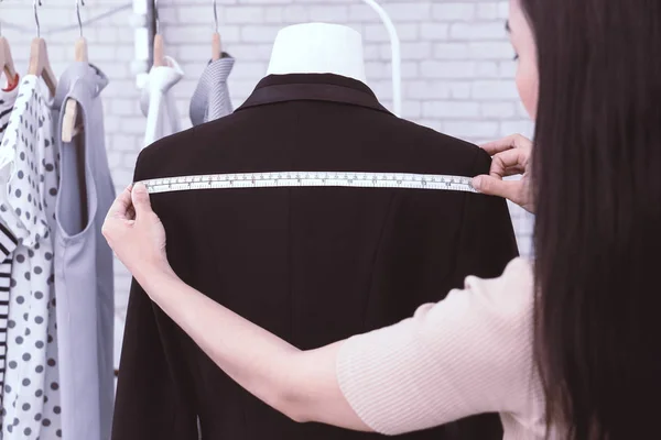 Japanese fashion designer is measuring jacket shoulder
