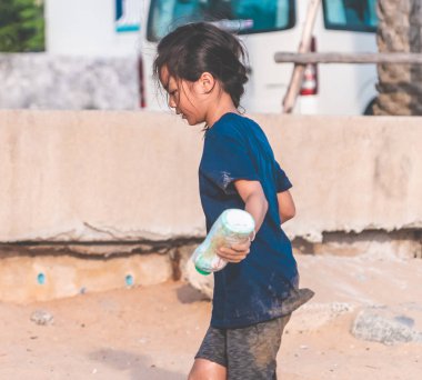 Çocuklar sahilde bulduğu plastik şişeyi tutuyor.