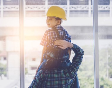 İnşaat kasklı çocuk babasının boynunda oturuyor.