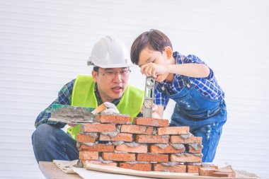 Baba müteahhit oğluna tuğla duvar örmeyi öğretiyor.