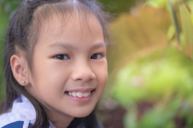 Mutlu Asyalı öğrenci yeşil bahçede oturuyor.