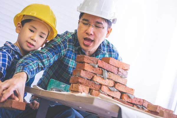 Маленький хлопчик вчиться будувати цегляну стіну зі своєї будівлі — стокове фото