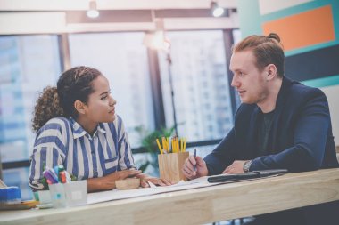 İki Genç Yaratıcı Pazarlamacı iş verileri üzerinde beyin fırtınası yapıyor.