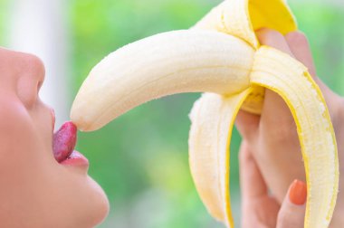 Asyalı kadın şehvet için sarı muzu yiyor ve yalıyor.