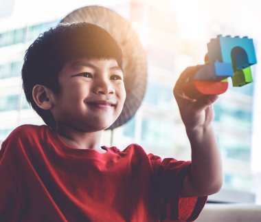 Oyuncak blokları eğitim için oturma odasına yığan mutlu çocuk.