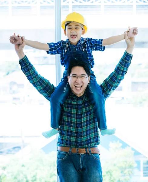 Padre sostiene a su hijo en su hombro con sombrero de construcción — Foto de Stock