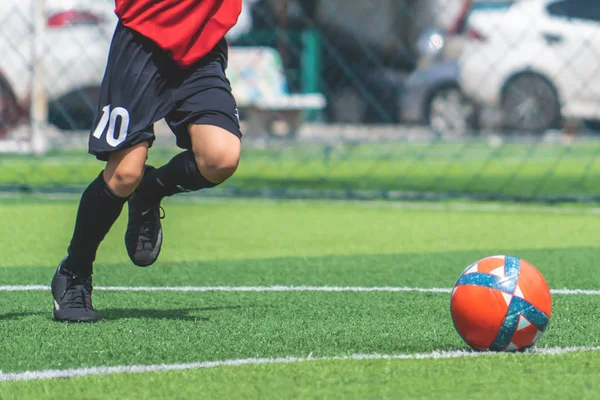 Футболист тренируется пинать мяч на футбольном поле — стоковое фото