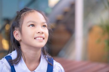 Mutlu Asyalı öğrenci dışarıda oturuyor.