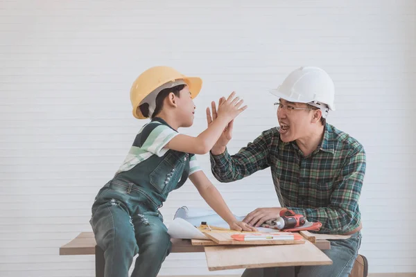 Padre es hola cinco con su hijo sobre el trabajo de madera y renovación de la casa — Foto de Stock