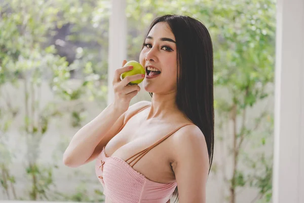 Güzel bir kadın yeşil elma yiyor. Mutlu bir yüzü var. — Stok fotoğraf