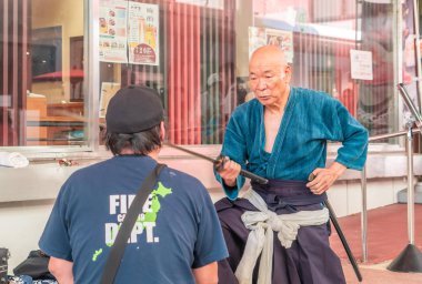 Japon kılıç ustası Katana 'yı nasıl örteceğini turistlere gösteriyor.