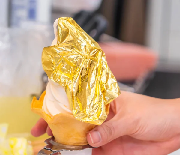 La mano está sosteniendo un helado de hoja dorada el helado de firma — Foto de Stock