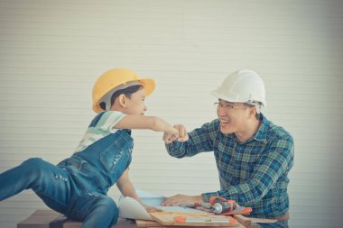 Asyalı bir ebeveyn, oğluyla ahşap işi yaparken yumruk tokuşturur. 