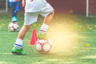 Little Kid is praticing in soccer football training session drib
