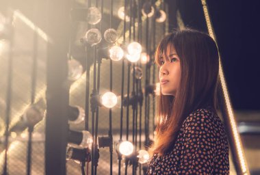 Açık havada Bokeh ışıklı arka planda bulanık duran bir kadının portresi 