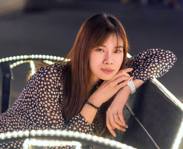 Retrato de una mujer sentada en la brillante luz de Bokeh sobre la decoración de la silla —  Fotos de Stock