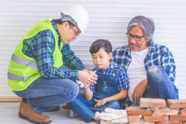 Küçük çocuk inşaatından tuğla duvar örmeyi öğreniyor.