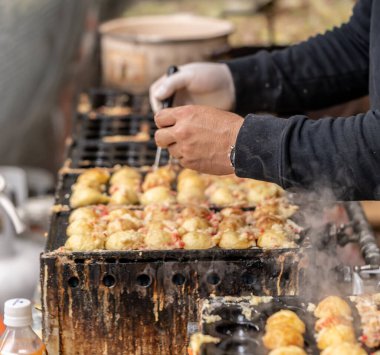 Satıcı Japon Takoyaki Ahtapot Topu pişiriyor..