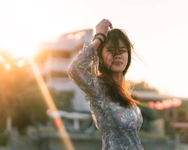 Yaz plajı rahatlama konsepti için arka planda plaj tatil köyü olan sert güneş ışığıyla birlikte kadın portresi..