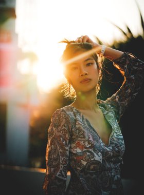 Sahildeki tatil köyünün arka planında yeşil ve turuncu renkli kadın portresi var..