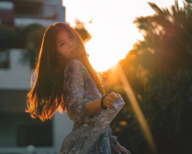 Güzel Asyalı kadın, özgürlük ve rahatlatıcı konsept için gün batımı hafif siluetiyle dans ediyor..