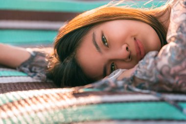 Asiam genç kadın plajda uzanmış, yaz rahatlama konsepti için, göz açıp kapayıncaya kadar güneşleniyor..