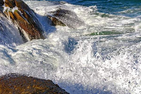 Zee water spray over de stenen — Stockfoto