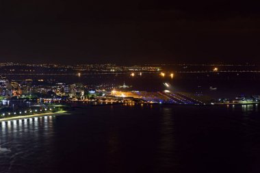 Gece şehir ışıkları, binalar ve Rio Niteroi Köprüsü'nde arka plan ile Rio de Janeiro Santos Dumont havaalanına üstündeki görünümünü