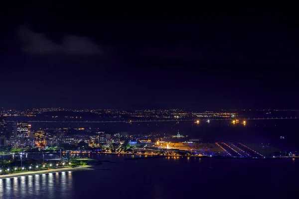 Gece şehir ışıkları, binalar ve Rio Niteroi Köprüsü'nde arka plan ile Rio de Janeiro Santos Dumont havaalanına üstündeki görünümünü