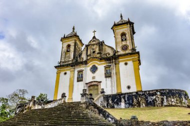 Eski ve yaşlı tarihsel kilisede yüksek eteklerindeki birkaç arka planda karanlık bulutlar ile Ouro Preto'daki şehir